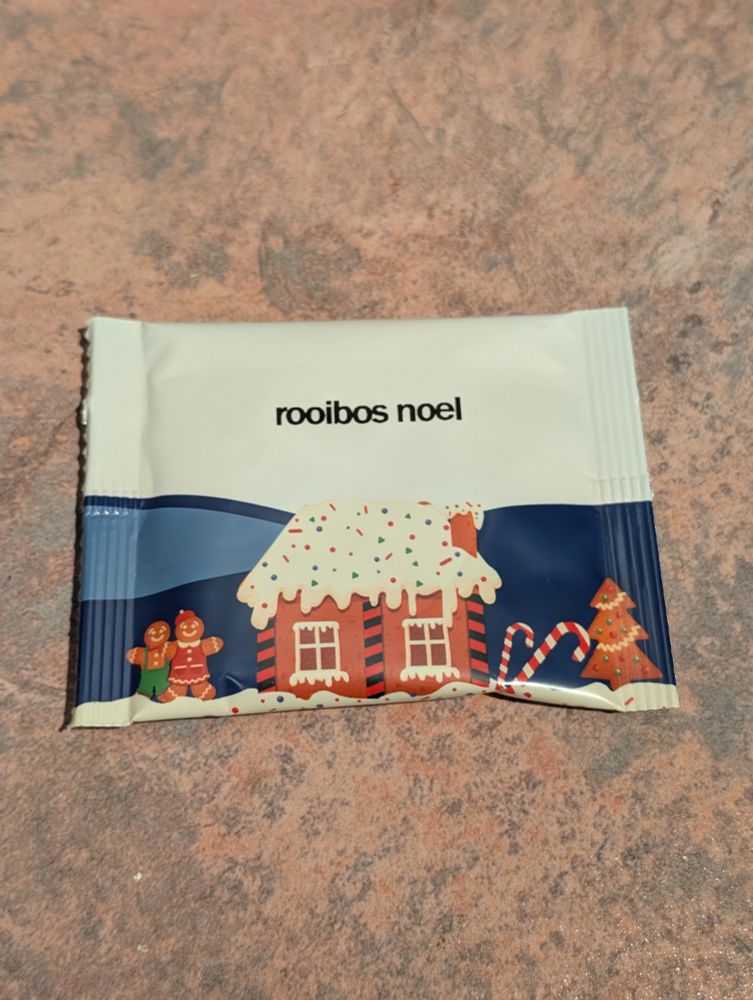 A white and blue tea packet with a picture of a gingerbread house and two gingerbread people