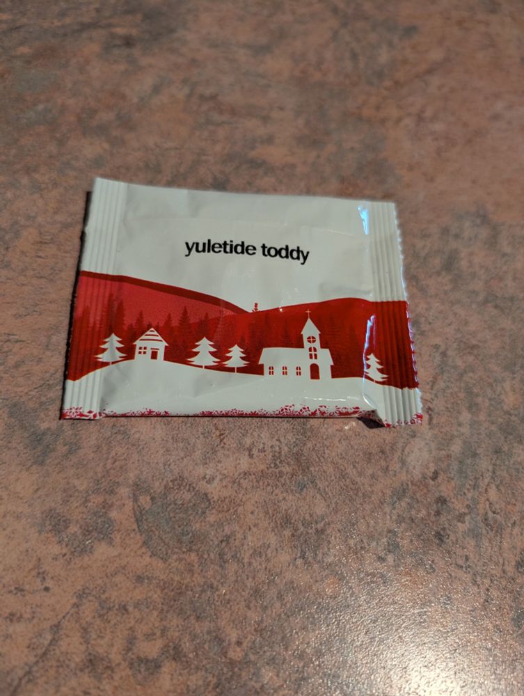 A tea packet with a white background, red hills, and white houses and trees. 