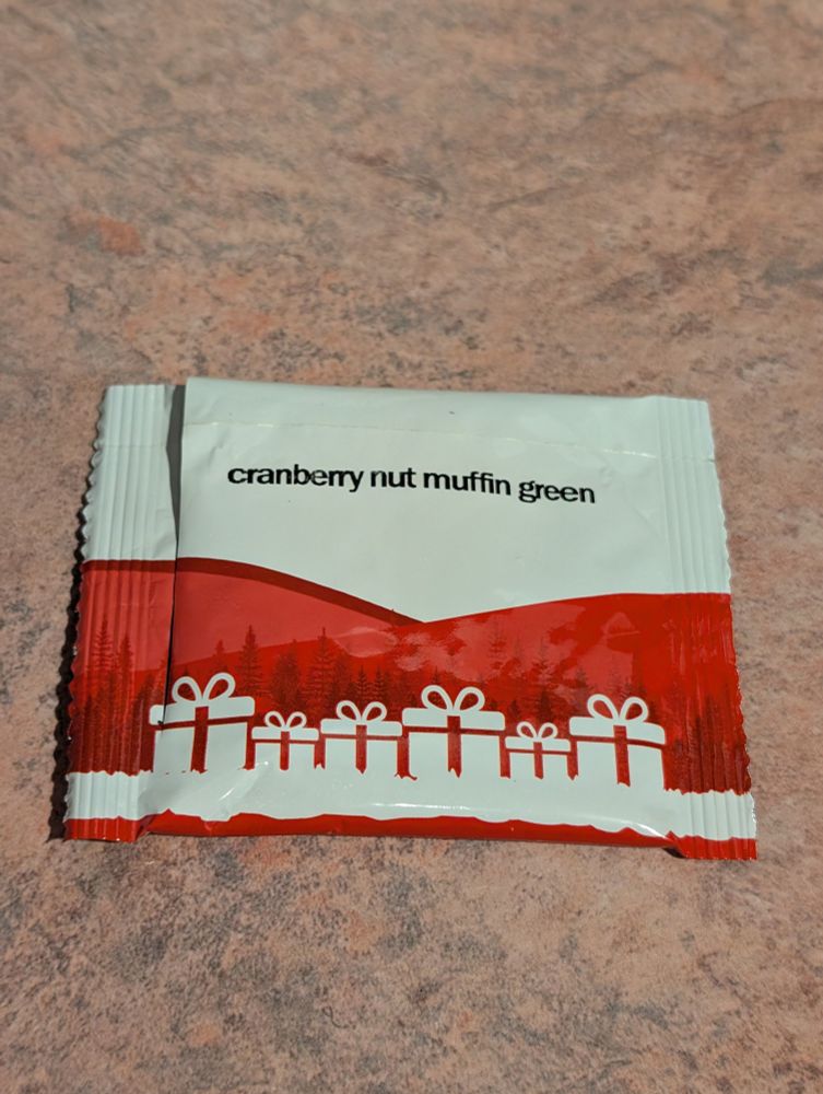A tea packet with white gift boxes in front of a red background