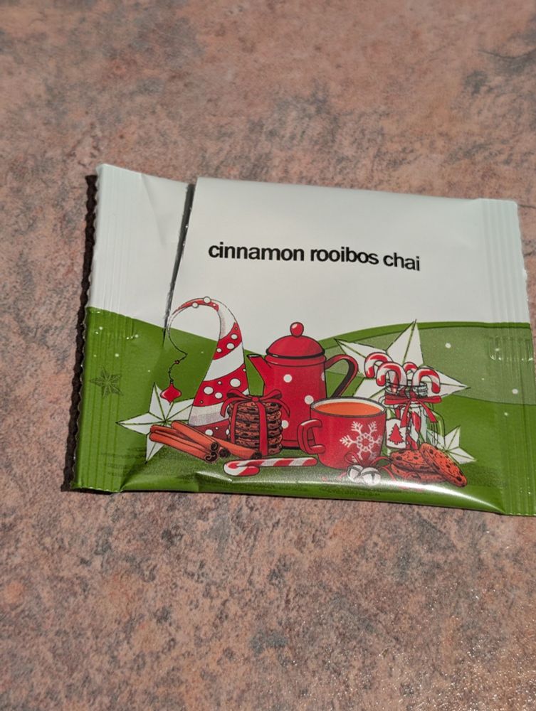 Green and white tea packet, with Christmasy red images - mug,cookies, candy canes, stars