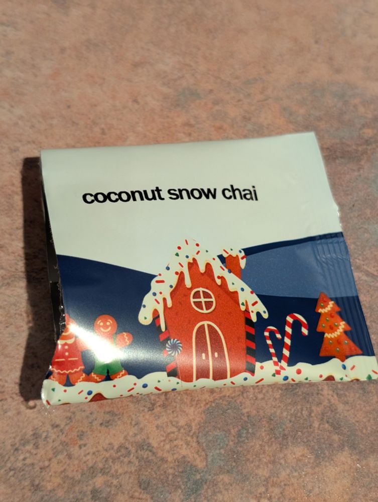 A blue and white tea packet decorated with a gingerbread house and two gingerbread people.