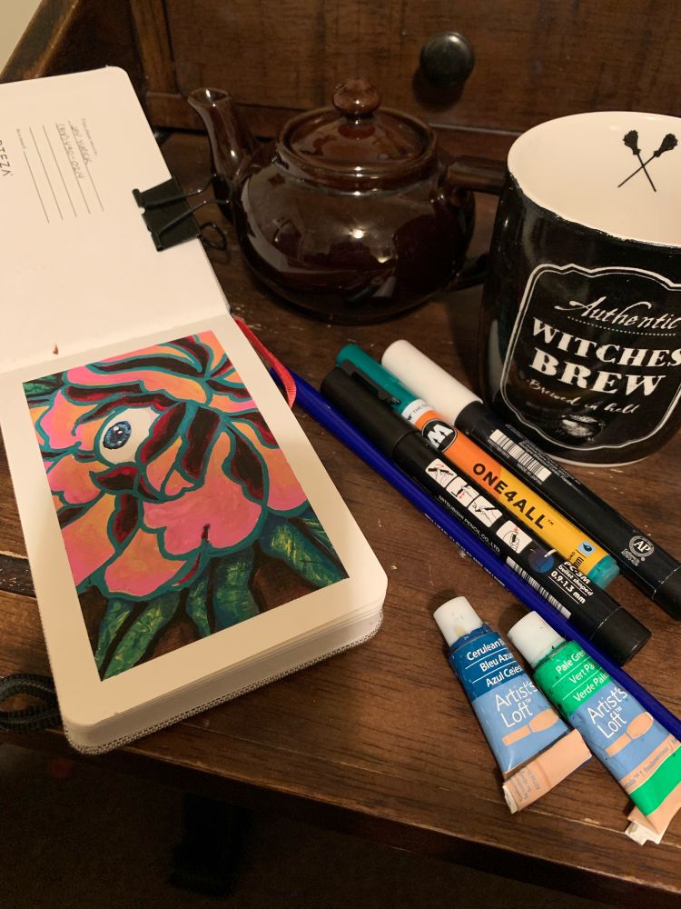 Eyeball flower painting beside a cup of tea