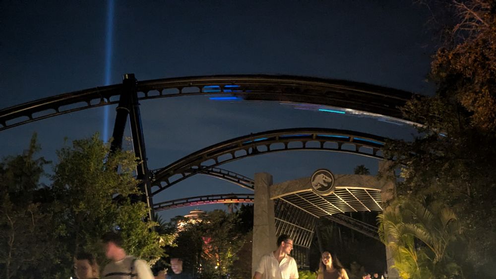 Velocicoaster's inverted stall from the side, with a car going through, in the nighttime.