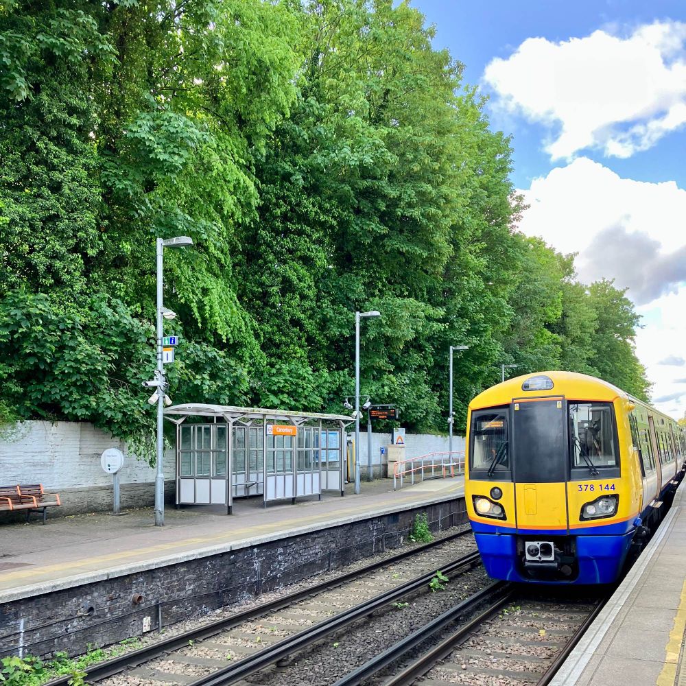 Alt text! Nice one. This is a pic of a train coming into a station in north London with a partly cloudy sky in the background. 
