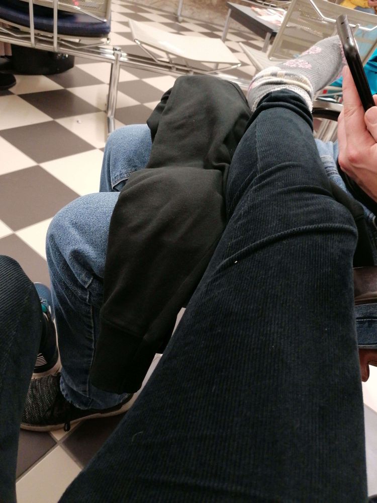 Auf dem Bild sieht man ein rechtes Bein in einer schwarzen Cordleggins, was über den Schoß einer anderen Person gelegt ist. Der Fuß am Ende des Beins steckt in einer grauen Kuschelsocke mit pinken Schneeflocken, auf dem Sockenschaft sind Faultiere zu sehen.

Der Boden hat ein großes Schachbrettmuster. Die Personen sitzen im Wartebereich eines Krankenhauses.