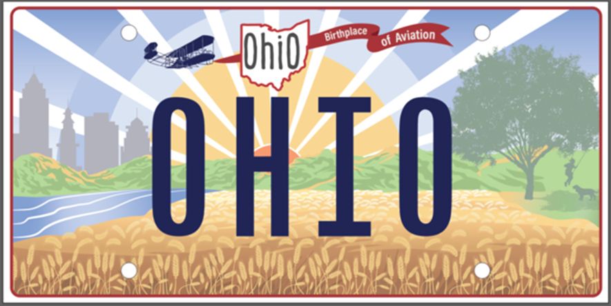 An Ohio license plate with the Wright Flyer flying over hills and a wheat field with trees and buildings and a stylized sun. 