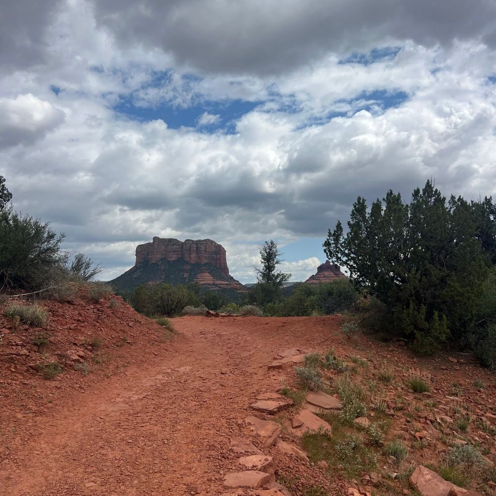 A picture of Courthouse butte in Sedona, Arizona. There are storm clouds brewing in a clear blue sky. 