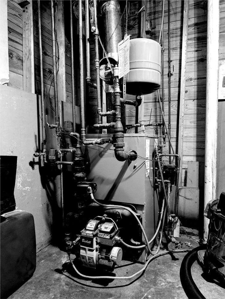 Black and white photo of a home's primary heating unit in the basement.