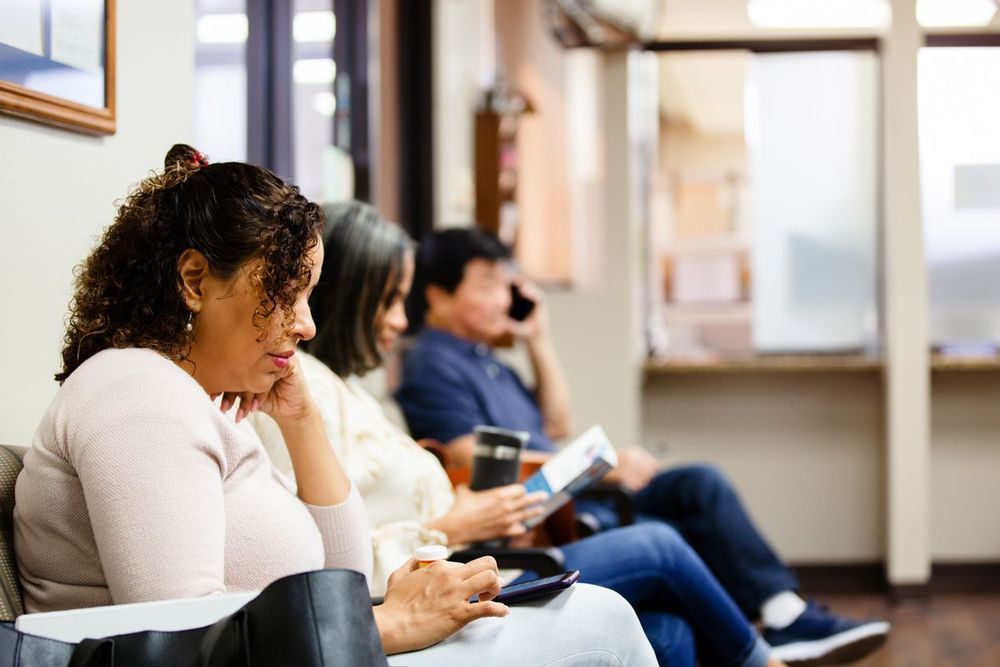 Women in the foreground with two people in the background waiting in a waiting room