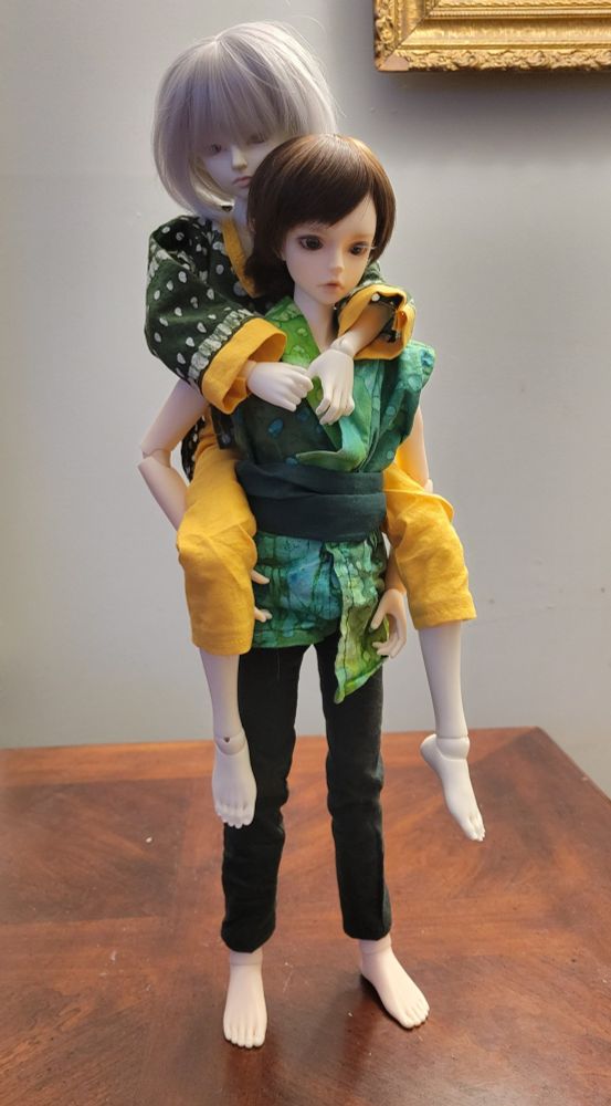One doll carrying another piggyback style with no additional supports
