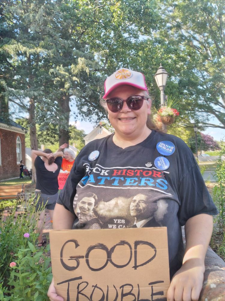 Me wearing my "Black History Matters" t-shirt and holding the cardboard sign I made in the car that reads "GOOD TROUBLE".
We assembled in the 400 yo historic courthouse circle in Gloucester County, VA and I am beside the old brick wall. There is also a lot of greenery surrounding me on this lovely summer day