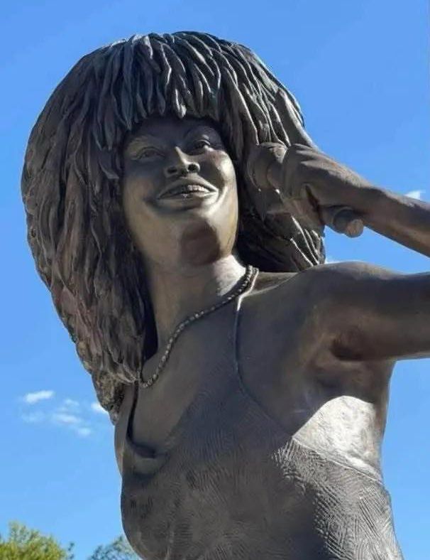 A bronze colored statue holding a microphone 