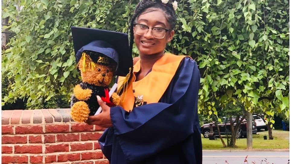 A photo of Ashanti Downey in her graduation gown, holding a bear 