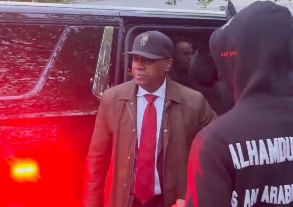 Newark Mayor Ras Baraka wearing a brown jacket, black hat, red tie 