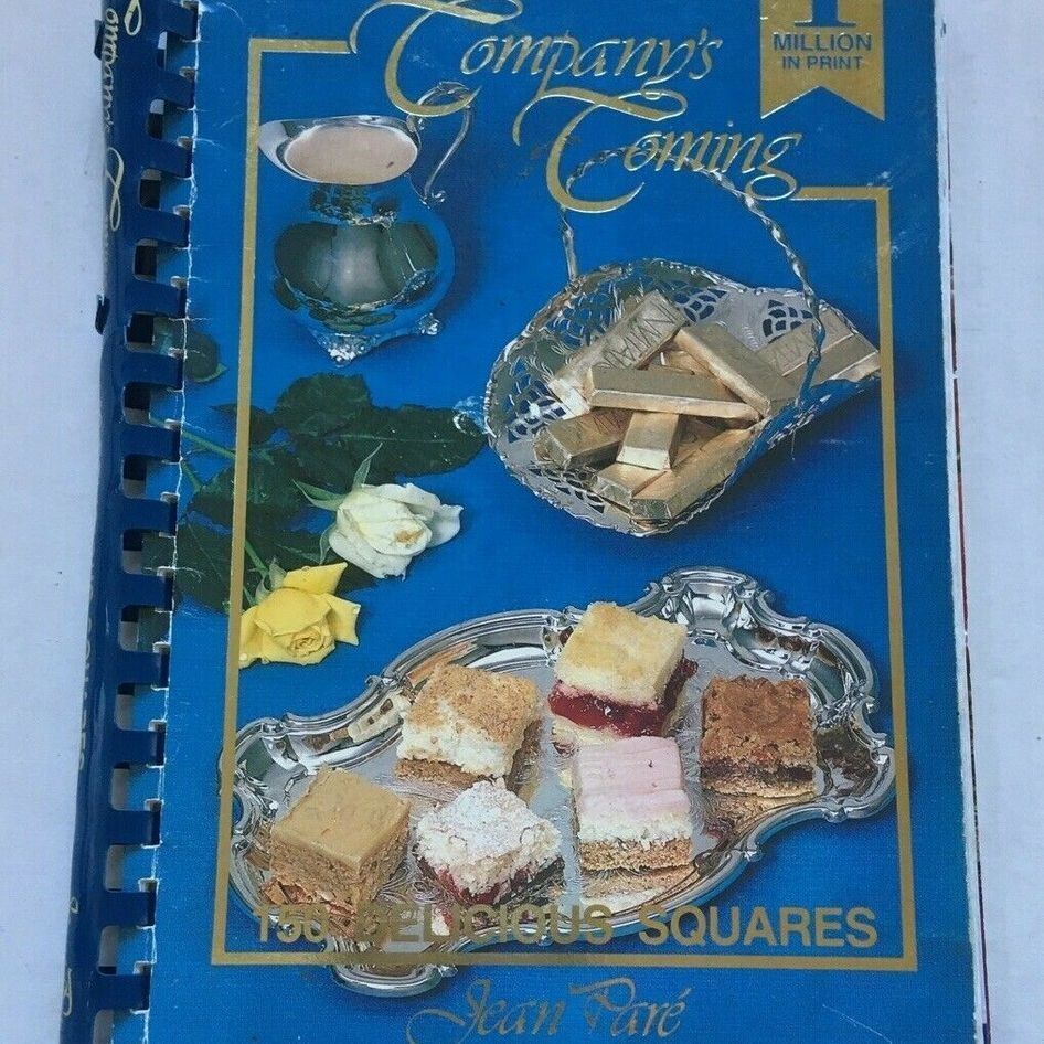 A well-worn blue spiral-bound cookbook titled "Company's Coming: 150 Delicious Squares" by Jean Paré. The cover shows a silver tray holding an assortment of colorful dessert squares, a silver basket of shortbread cookies, a silver cream pitcher, a white rose, a yellow rose, and green leaves against a bright blue background. A gold banner in the top right reads "OVER 1 MILLION IN PRINT." The book shows visible wear on the edges and spine.