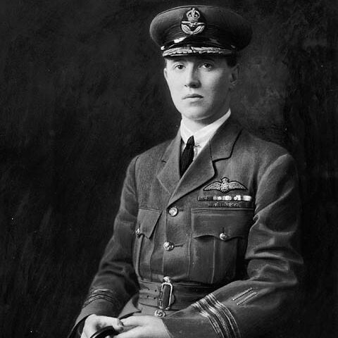 Black-and-white portrait of a young man in RAF uniform with peaked cap, pilot wings, and medals.