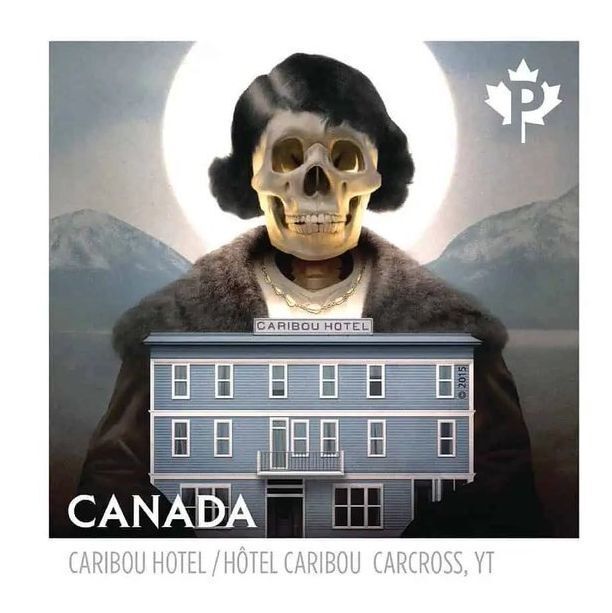 A Canadian postage stamp featuring an artistic depiction of the Caribou Hotel in Carcross, YT. The stamp shows a surreal image with a skull wearing a dark wig and fur collar, positioned above the hotel. The hotel is a multi-story blue building with a sign reading "CARIBOU HOTEL" on the roof. The background includes mountains and a glowing full moon. The stamp is marked with "CANADA" and a maple leaf symbol with "P" in the top right corner, and the text "CARIBOU HOTEL / Hôtel CARIBOU CARCROSS, YT" is at the bottom.