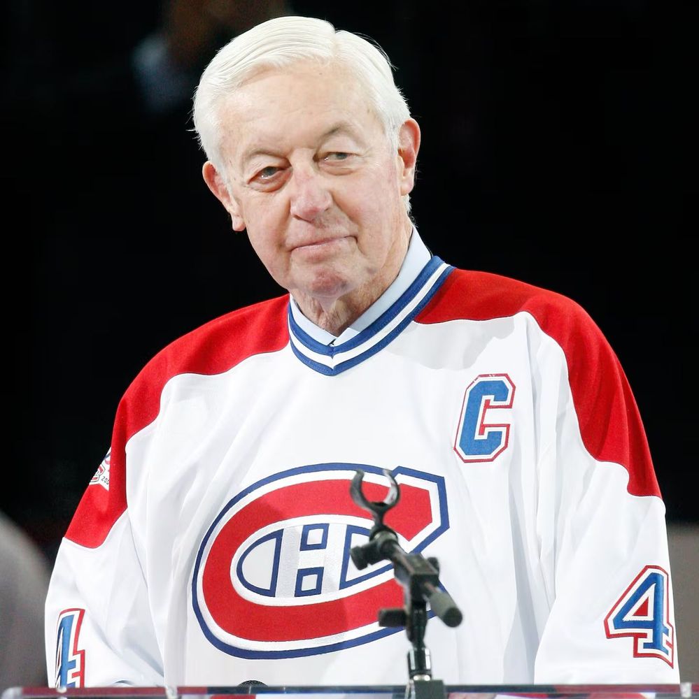 The photo shows Jean Béliveau, wearing a Montreal Canadiens jersey with the number 4 and a captain's 