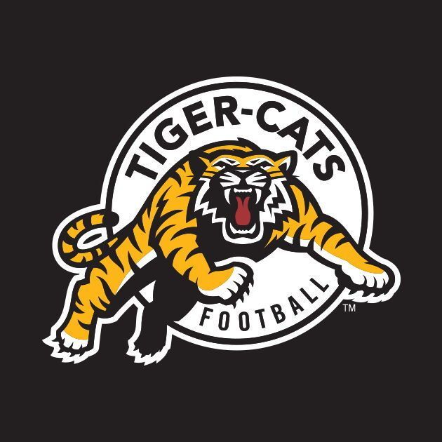 A logo featuring a fierce orange tiger with black stripes, white accents, and an open red mouth roaring, leaping forward in a dynamic pose. The tiger is centered within a white circular border on a black background. Bold black text "TIGER-CATS" arches across the top of the circle, "FOOTBALL" along the bottom, and a small "TM" trademark symbol at the lower right.