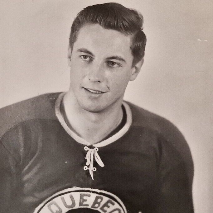 The photo shows Jean Béliveau wearing a Quebec Aces hockey jersey with a circular logo featuring the text 