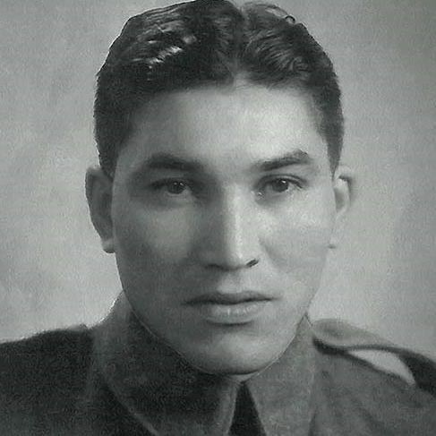Black-and-white portrait photo of a young man in military uniform, with short dark hair combed back, high collar, epaulets, and buttoned jacket with chest pockets. He faces forward with a neutral expression. Plain light background.