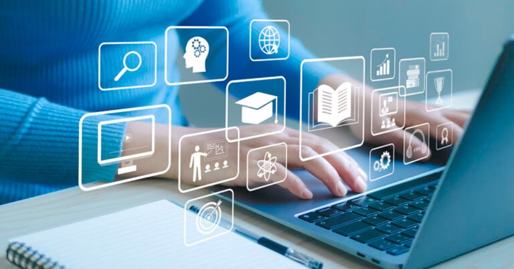 Person working on a laptop with digital icons of education and technology floating around them. There is a notebook and pen on the table.