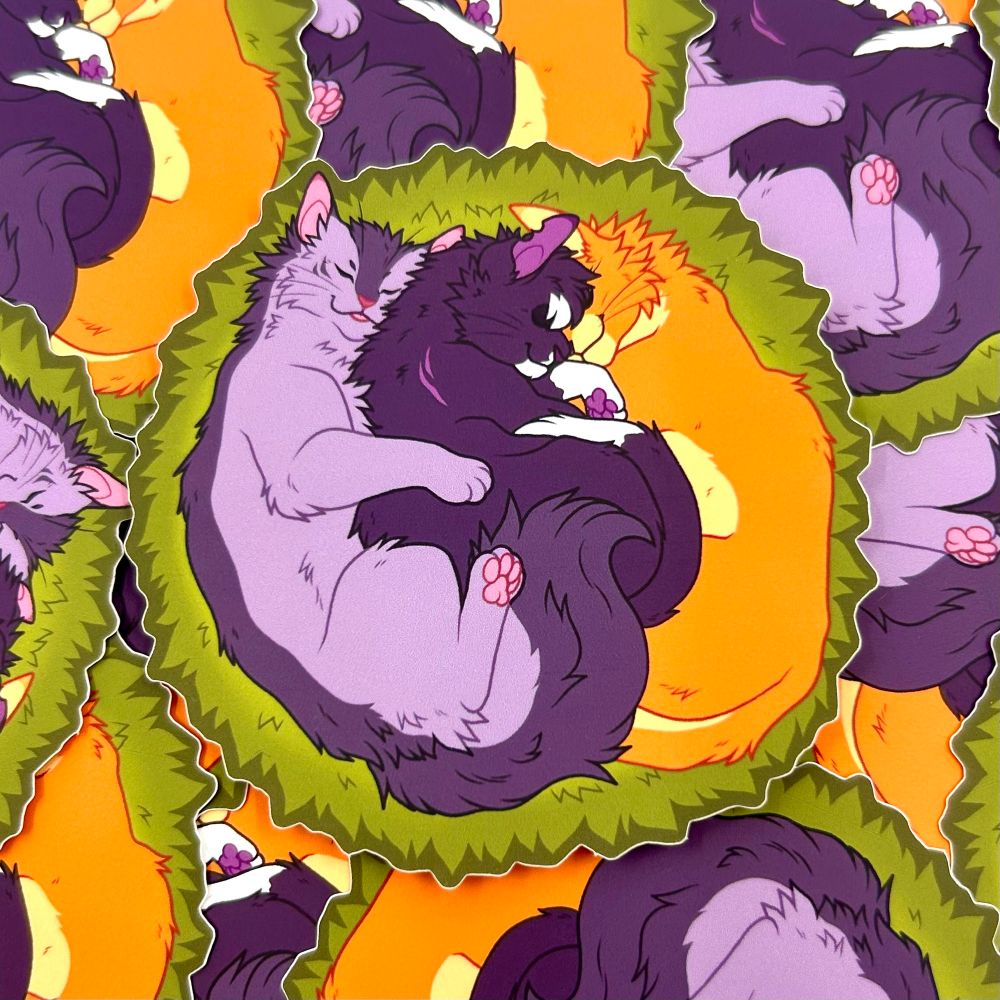 A pile of stickers, the top one being a gray cat, a black and white cat, and an orange cat cuddling in a moss nest