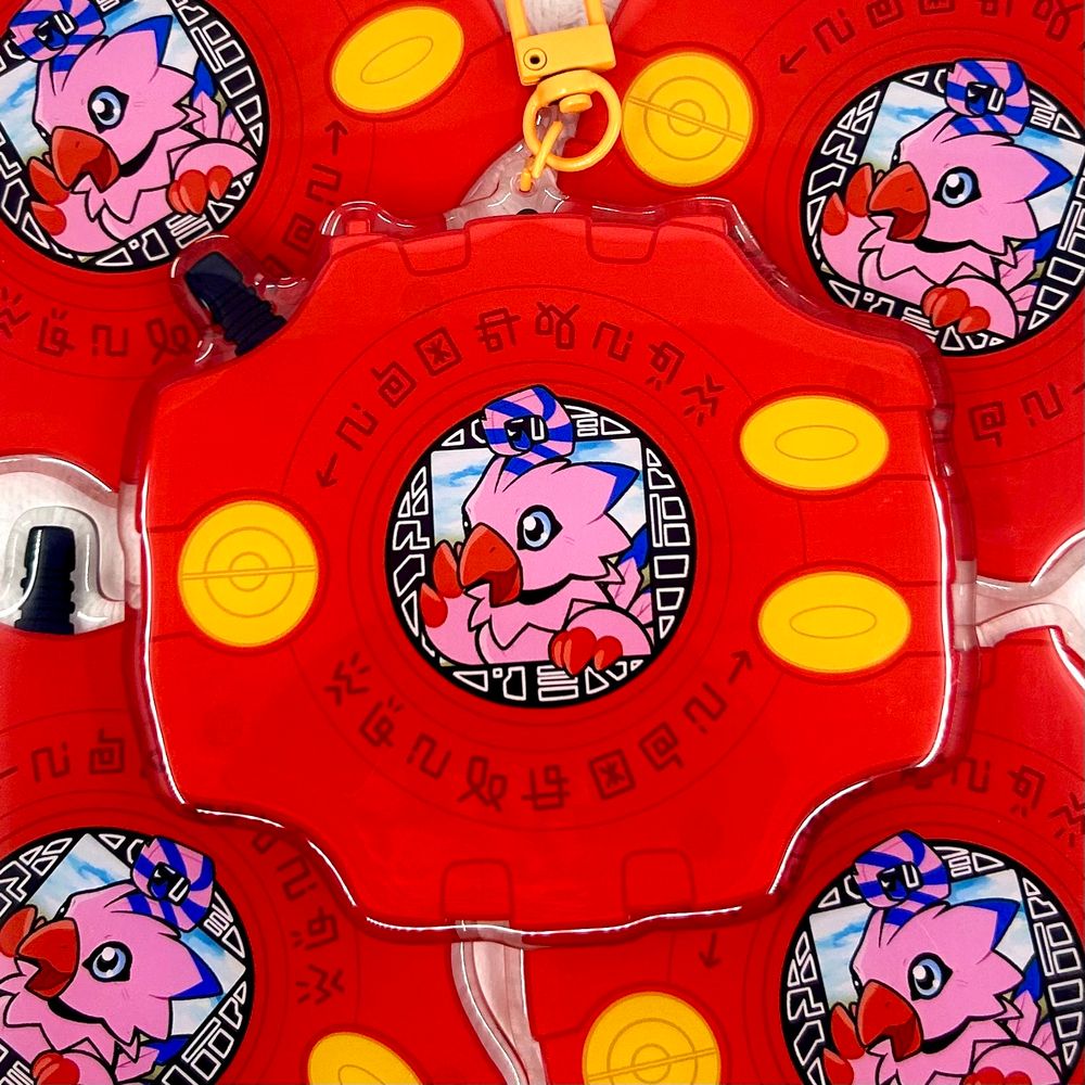 A pile of keychains of biyomon poking out of a red digivice