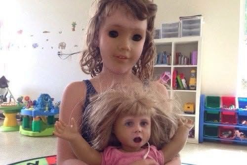 photo of a child holding a baby doll but they face swapped and the results are horrifying to say the least