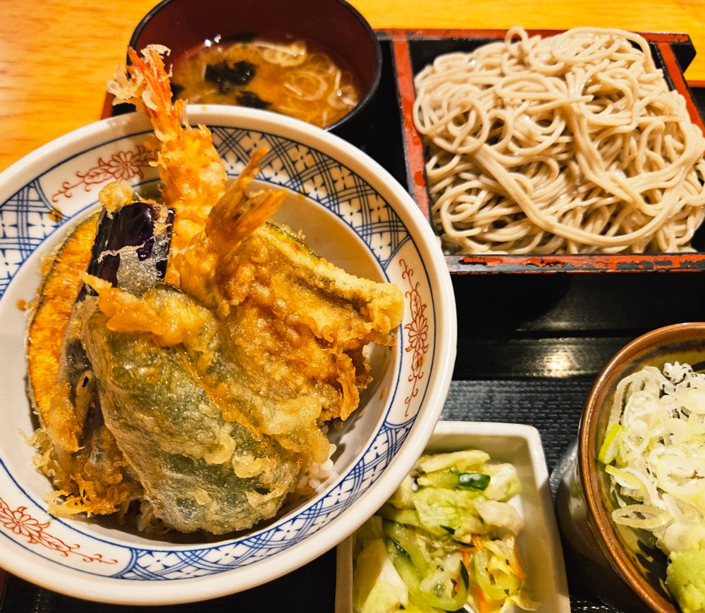 天丼、あおさの味噌汁、ざるそば、そばつゆの器に重ねられた小皿の上のねぎとわさび、きゅうりと白菜とにんじんの漬物