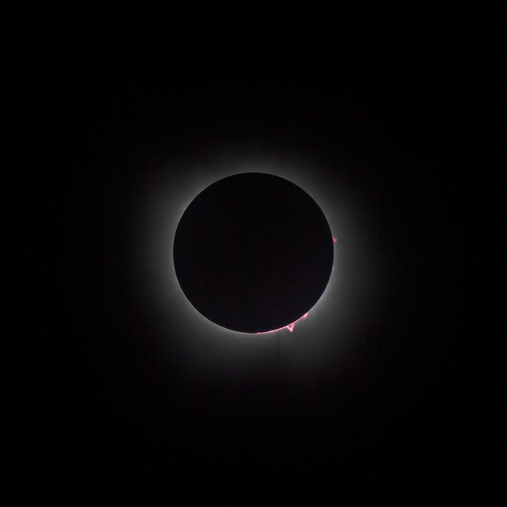 Almost total eclipse with solar prominences peaking out like little flames