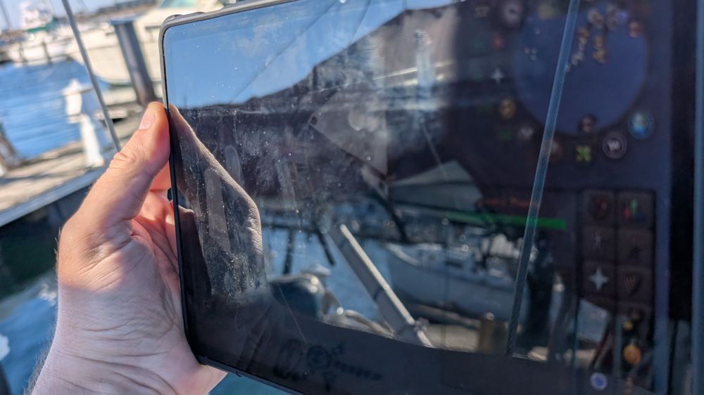 A picture of a guy holding a tablet on a boat.  You can kinda see the Oldschool RuneScape interface but tbqh it's reflecting the boat more than displaying anything.