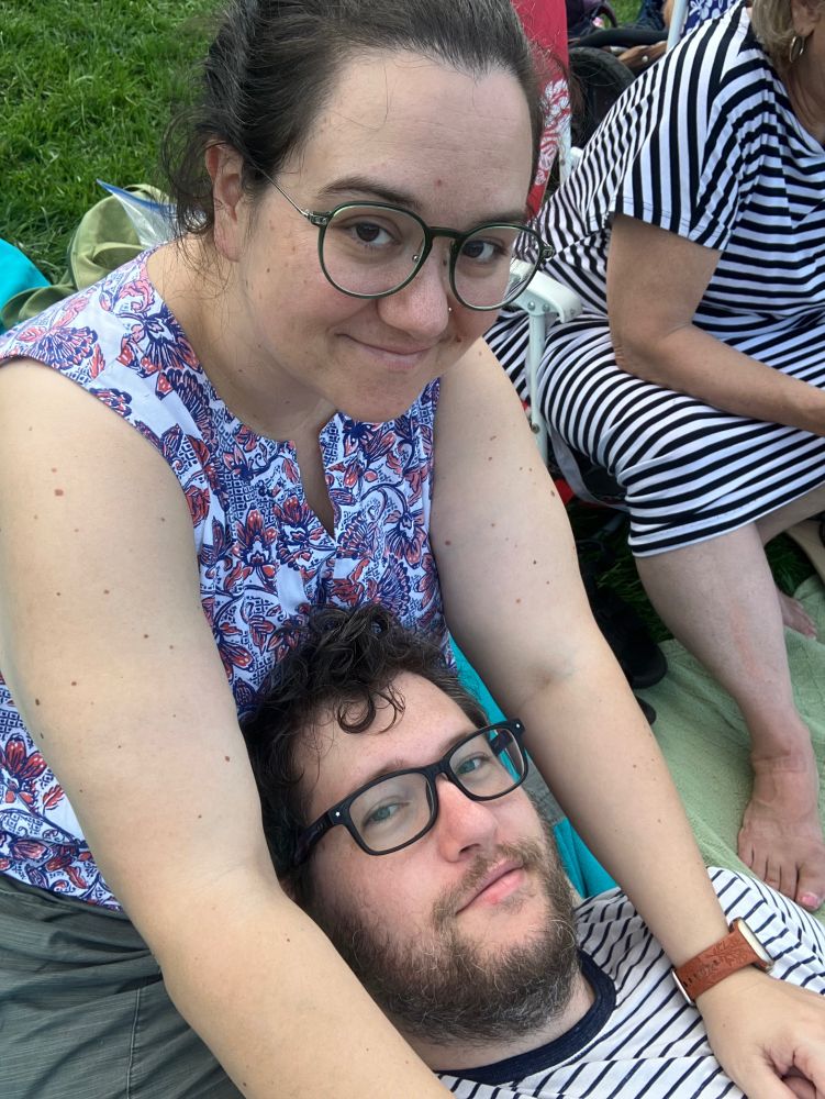 A woman and a man on the grass at an outdoor amphitheater. 2023.