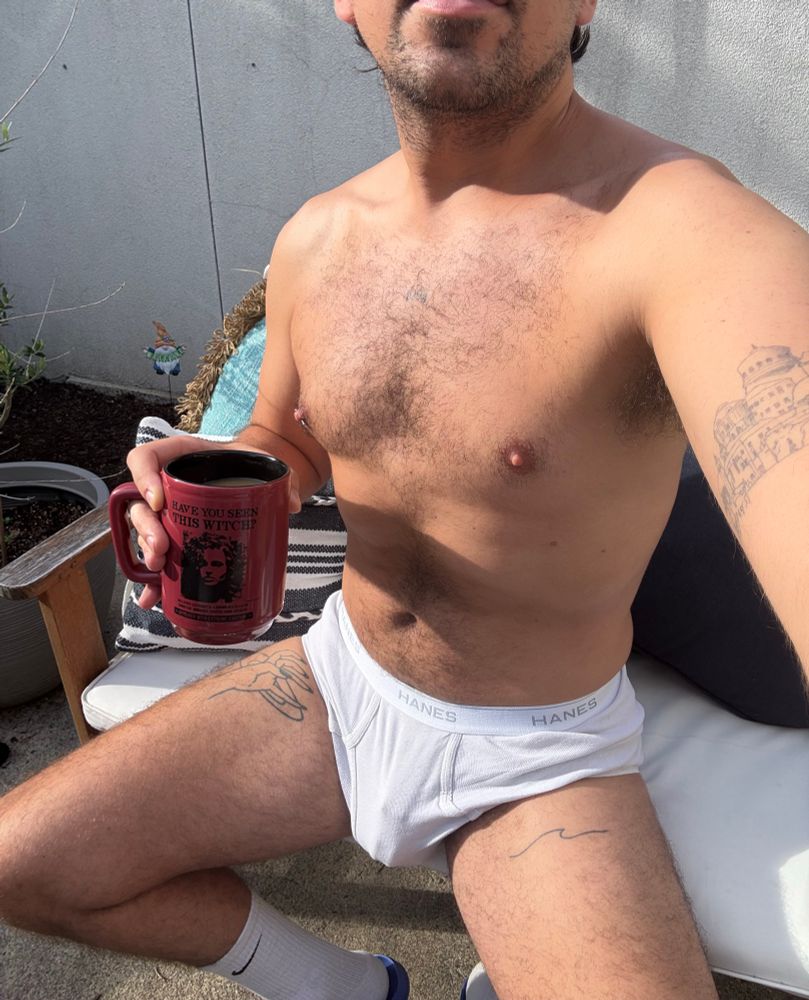 Cage print in Hanes tighty whities briefs sitting outside in the sun on patio furniture holding coffee mug