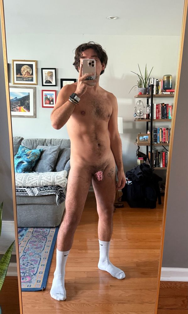 Mirror photo standing naked in white Nike socks and pink cage with phone obscuring face 