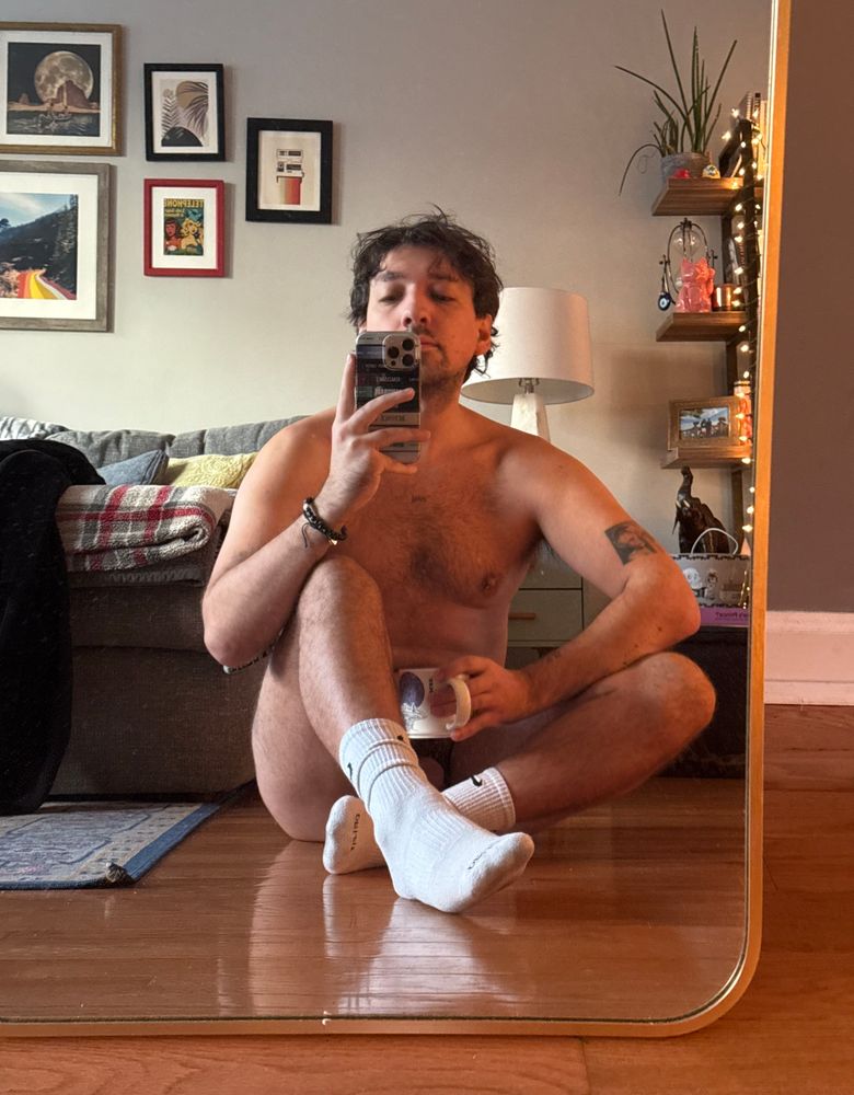 Sitting naked in socks on the floor holding coffee mug