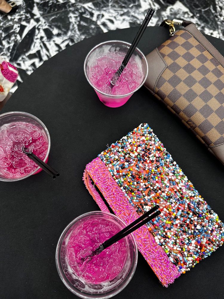 3 Pink alcoholic drinks and clutch purses on a cocktail table 