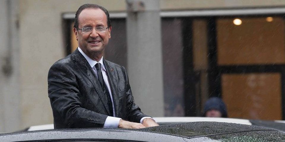 Hollande post diet drenched in the rain, standing through the open roof of a sedan smiling. 