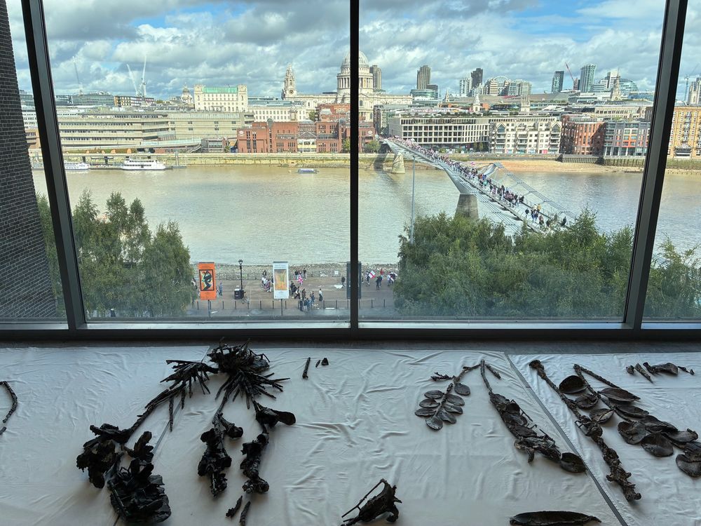 A view of London, taken from the Tate Modern. A large group of people, some holding British flags, can be seen on a bridge.