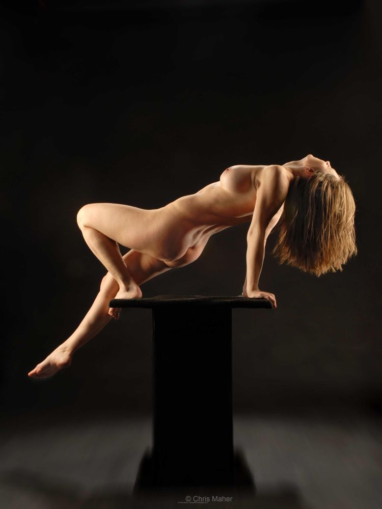 Naked woman, balancing herself on a small platform.