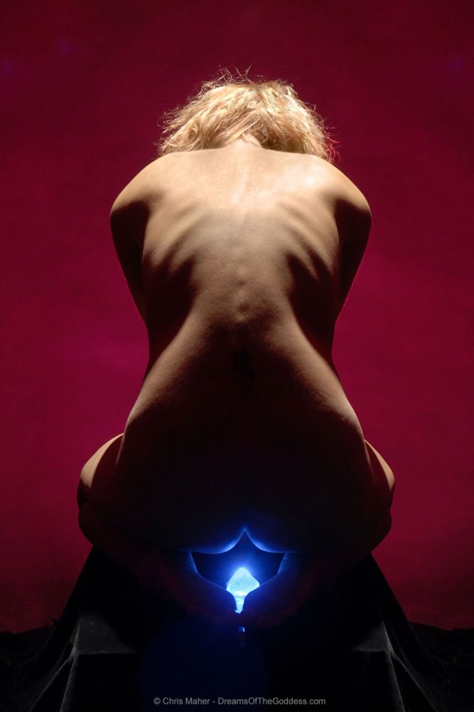 A woman’s sits, her back to the camera. She is illuminated in warm light, but below her is a crystal ice.