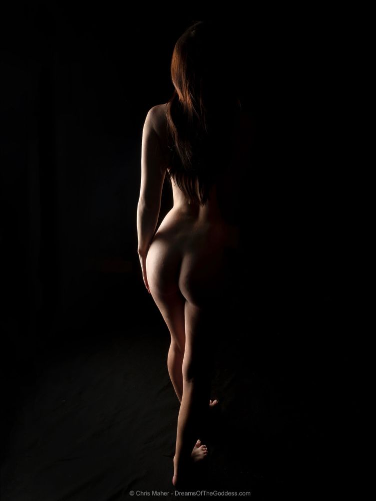 A woman’s nude body is illuminated on one side with a soft glowing light.