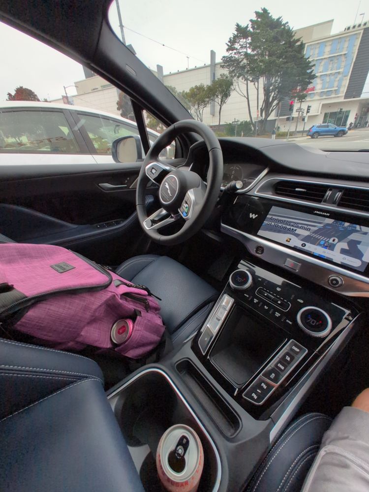 A picture of a backpack in the empty driver seat of a self driving car.