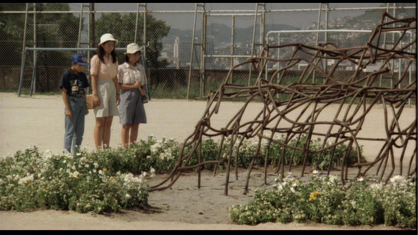 Three Japanese youth look at the twisted remains of a school jungle gym struck by the atomic bombing of Nagasaki. Scene from Kurosawa's Rhapsody in August.