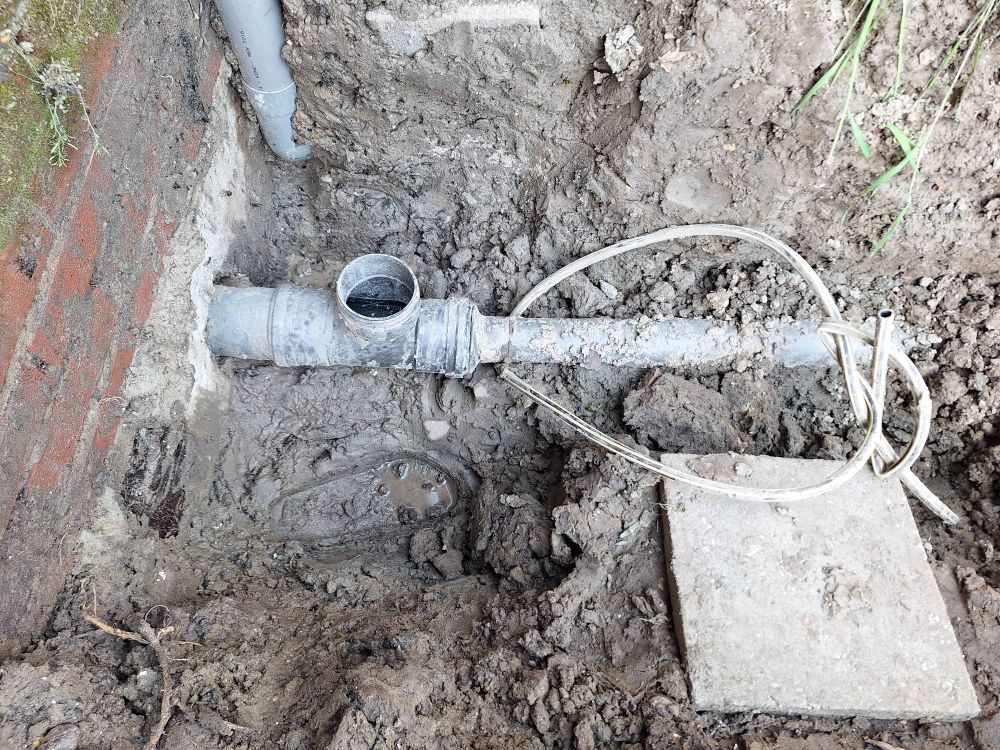 De uitgegraven rioolpijp die uit m'n muur komt. Het is een meter diep.