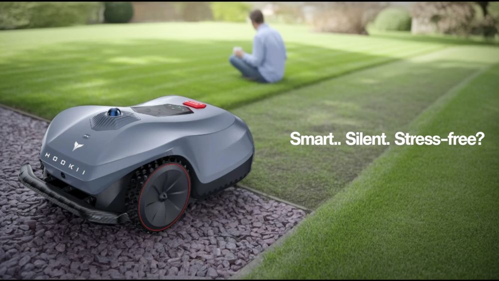 Robot lawnmower with person in background sipping coffee