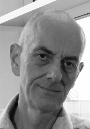 A predatory-looking bald man stares menacingly at the camera 