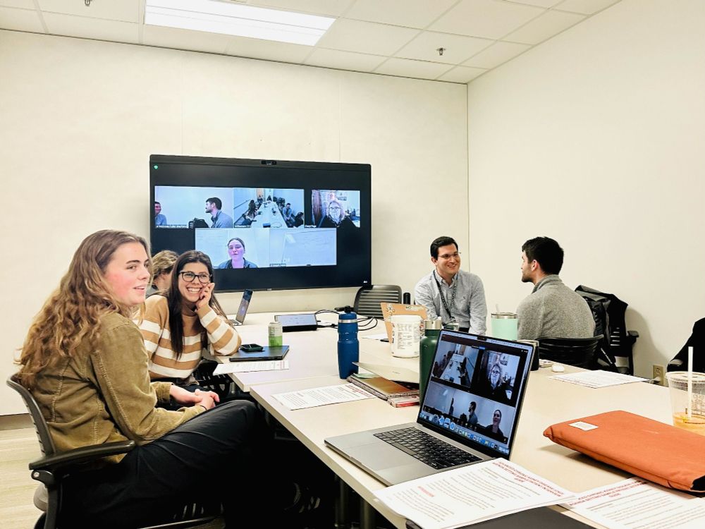 A group of researchers practicing interviewing at a long table. 