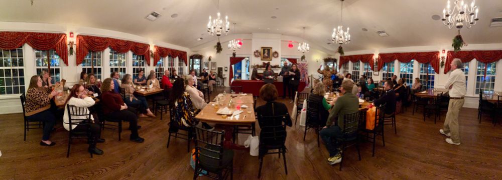 CS4 participants sit at tables at the Boston Tea Party Museum listening to a speaker 