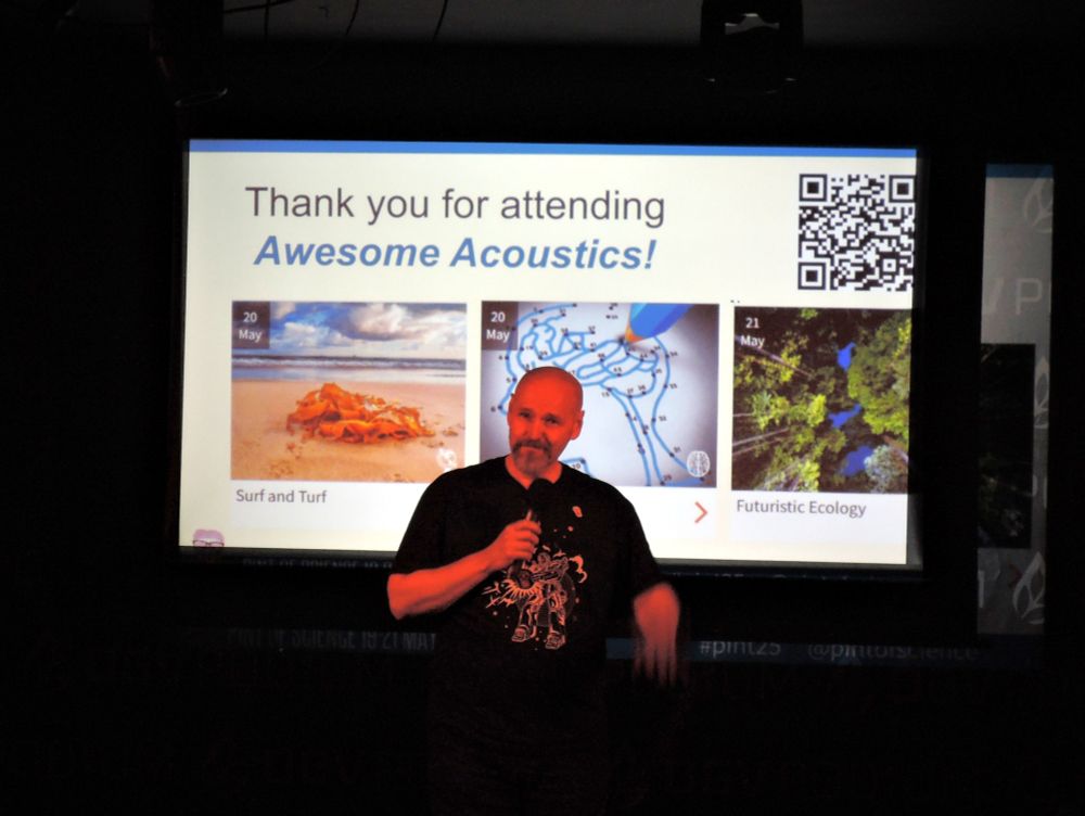 Presenter with microphone in front of screen showing a "hanks for attending" message